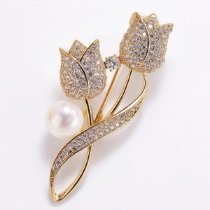 Détail d'une broche tulipe dorée sertie de zircons blancs et d'une perle ronde élégante