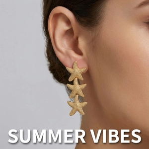 Macro shot of gold starfish drop earrings featuring a detailed grainy texture on the model