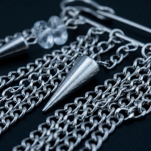 Detailed close-up of punk style multi-layer silver metal chain brooch with spike pendants