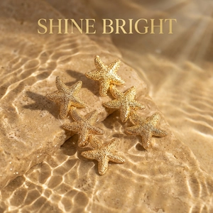 Close-up of triple layered gold starfish earrings with textured matte finish on sea rocks