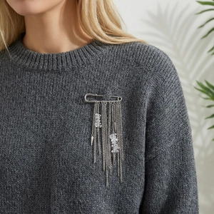 Silver tassel safety pin brooch with hanging chains and crystal charms on a grey sweater