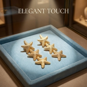 Macro detail of six golden starfish earrings featuring fine textured matte finish on blue velvet