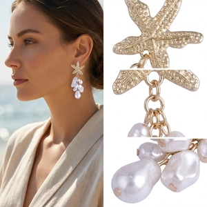 Detalle de pendientes de estrella de mar dorada con perlas barrocas en la playa