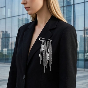 Close-up of silver safety pin brooch with long chains and crystal pendants on black suit