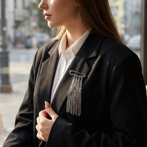 Silver pin brooch with layered metal tassels shown on a dark suit lapel