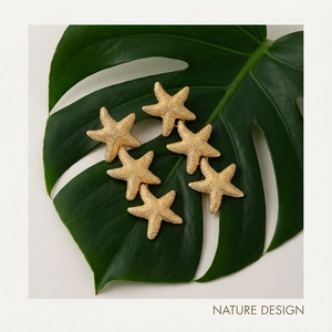 Detailed macro view of triple starfish gold earrings on a green monstera leaf backdrop