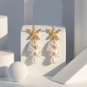 Detalle de pendientes de estrella de mar dorados con borlas de perlas barrocas blancas puras