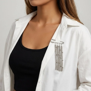 Silver pin brooch with long chain tassels worn on a white shirt collar for elegant style