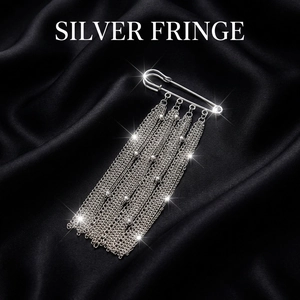 Detailed close-up of a silver fringe brooch with tassels and beads on black silk fabric