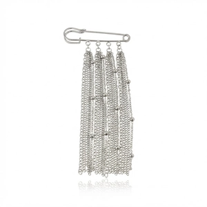 Close-up of a silver safety pin brooch with hanging metal chains and bead tassels