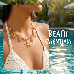 Detail of golden starfish and seashell charms on necklace worn over white beachwear