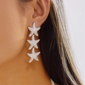 Macro detail of silver-tone starfish dangle earrings with sparkling pavé crystals