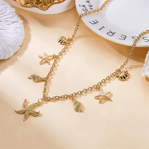 Close-up of golden starfish and shell charms on a delicate metal necklace with coral accents