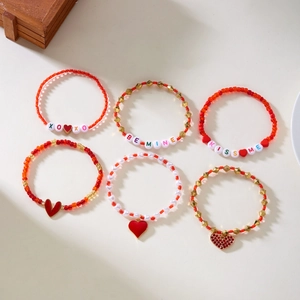 Detail van 6-delige Valentijn armbandenset met XOXO-kralen en rode hartjes hangers