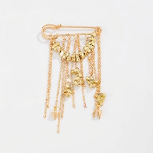 Close-up of golden tassel brooch pin with cascading chains and metallic accents