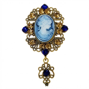 Detail of vintage relief lady brooch with blue stones and hollow gold-tone metal frame