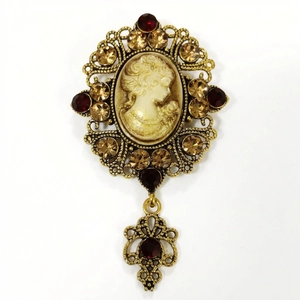 Macro shot of vintage cameo brooch with intricate gold openwork and red rhinestones