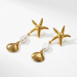 Detalle de pendiente de estrella de mar y colgante de concha con perla barroca blanca