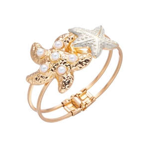 Detail of a gold starfish bracelet with white pearls and textured metallic finish