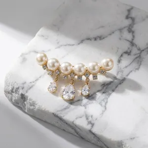 Macro detail of luxury pearl brooch with hanging water-drop rhinestones on marble