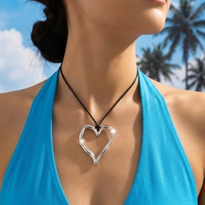 Irregular hollow heart pendant necklace with black wax rope on a beach model
