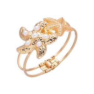 Detailed side view of golden double starfish bangle with white pearls and hammered texture