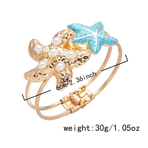 Detail view of gold starfish bangle with pearls and blue enamel and size markings