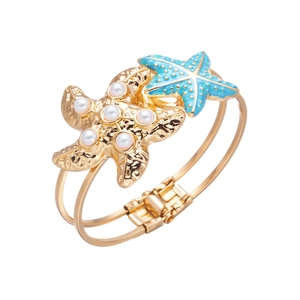 Detailed macro view of a gold starfish bangle with blue enamel and white pearls