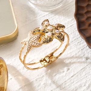 Detail of starfish bangle with pearls on white texture and vintage props