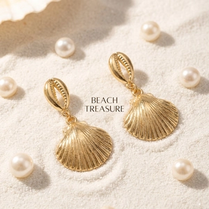 Detalle de los pendientes de concha dorados sobre un fondo de arena de playa