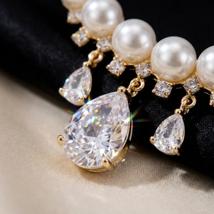 Detailed macro view of white pearls and sparkling teardrop crystals on a golden brooch base