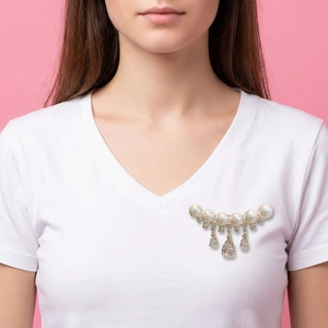Detailed view of elegant pearl brooch with teardrop rhinestones on white t-shirt
