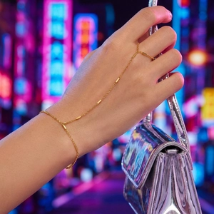 Dettaglio di un bracciale con anello dorato indossato da una modella con borsa argento
