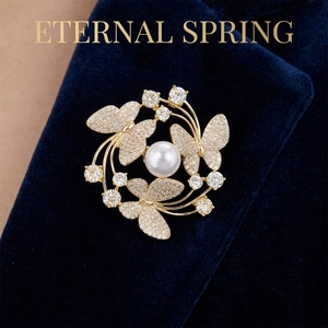 Close-up of golden butterfly brooch with white pearl on navy velvet blazer lapel