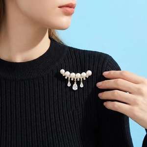 Elegant pearl brooch with water drop pendants on black knit sweater close-up
