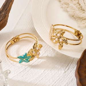 Detailed view of starfish bracelets with turquoise enamel and pearls on sand