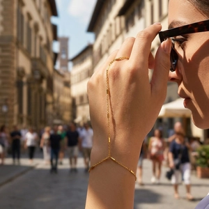 Dettaglio di un bracciale anello dorato con maglie rettangolari sulla mano di una donna