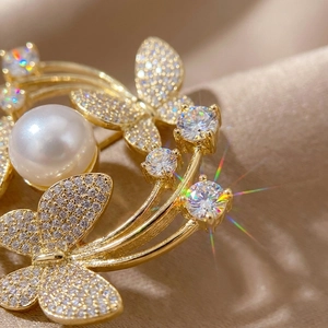 Macro shot of butterfly brooch with sparkling zircons and a large white pearl detail