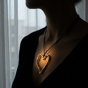 Macro detail of artistic gold hollow heart pendant on a black cord necklace