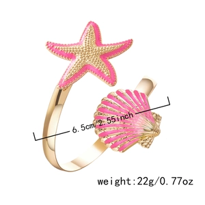 Macro shot of gold starfish and shell ornaments with pink enamel and sea-inspired design