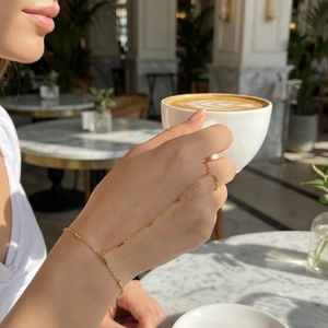 Elegante bracciale con anello dorato e dettagli a catena indossato da una modella