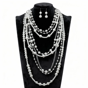 Detalle de conjunto de collar de perlas multicapa y pendientes en exhibidor de terciopelo