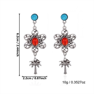 Detail view of bohemian turquoise drop earrings with floral patterns and palm tree charms