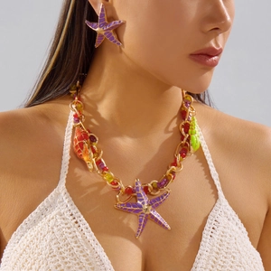 Detail of purple starfish earrings and beaded necklace worn by a woman for beach style