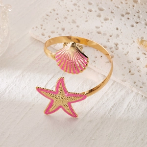 Detail of gold starfish and pink shell charms on a summer ocean style open bangle