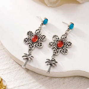 Detail view of bohemian turquoise drop earrings with silver flower and coconut tree charms
