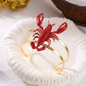 Detailed view of creative red lobster bangle with golden metal frame on seashell tray