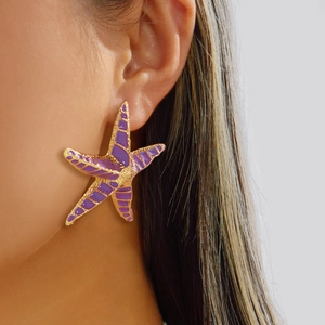 Close-up of bohemian starfish earrings with gold metal frame and purple glazed finish