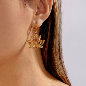Detailed view of bohemian gold lotus earrings with red and white crystals on a model