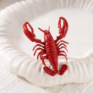 Detailed macro shot of a vivid red lobster ring placed on a textured white seashell tray
